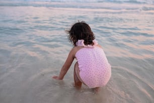해변에서 물속에 앉아 있는 어린 소녀
