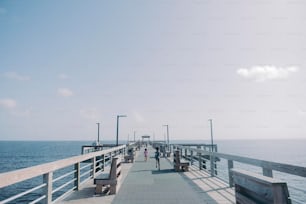 a pier with benches and people walking on it