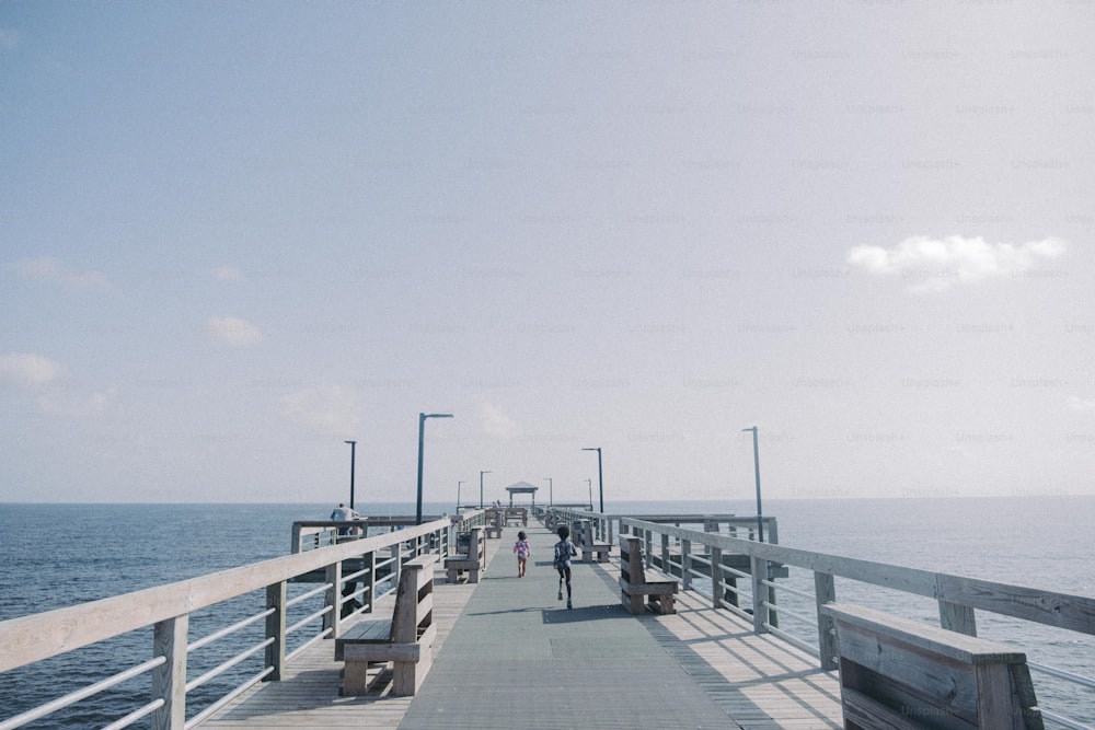 a pier with benches and people walking on it