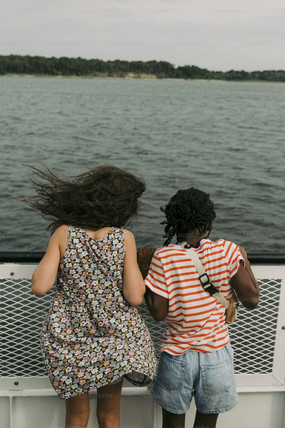 Zwei junge Mädchen, die auf einem Boot stehen und auf das Wasser blicken