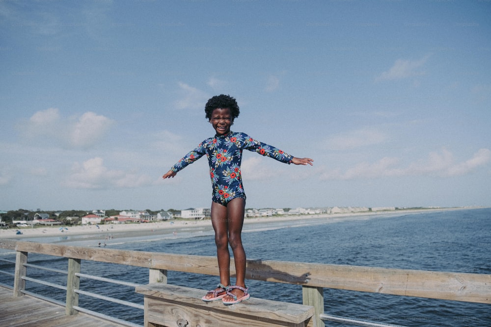 a young girl standing on a wooden pier
