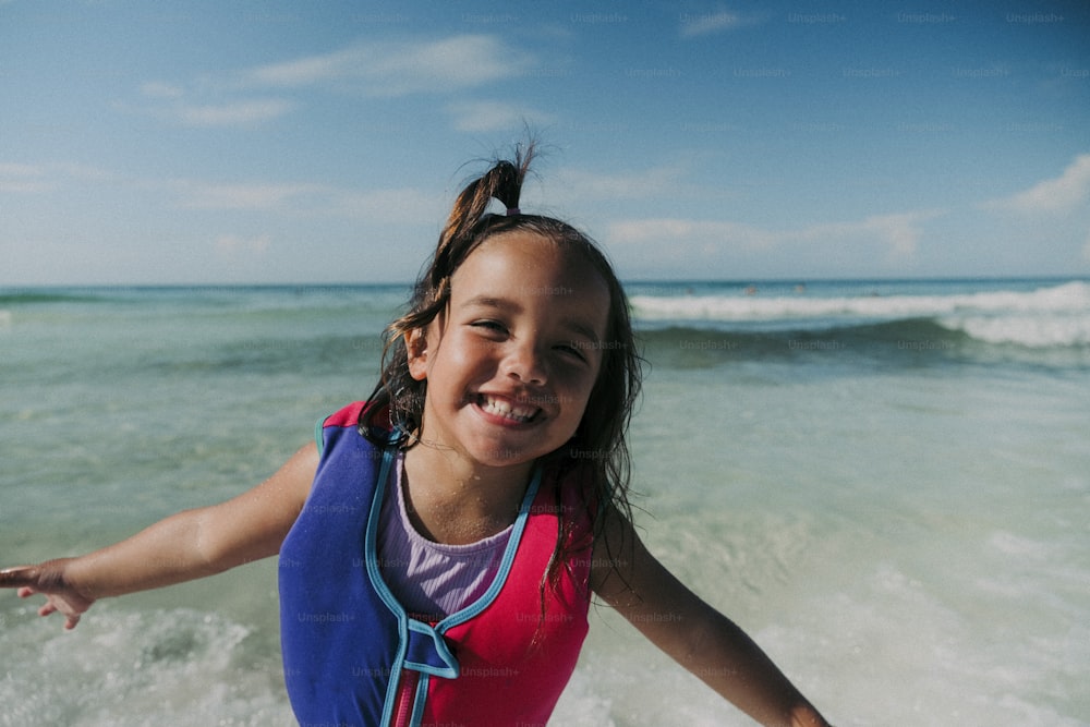 a young girl smiles as she rides a surfboard