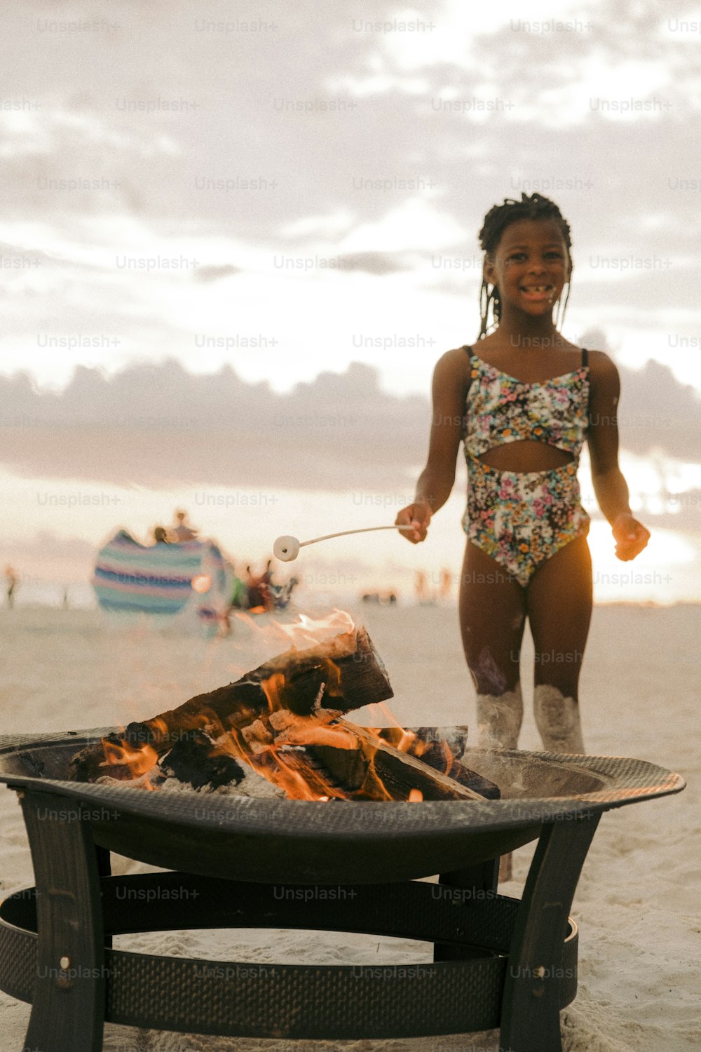 a little girl standing next to a fire pit