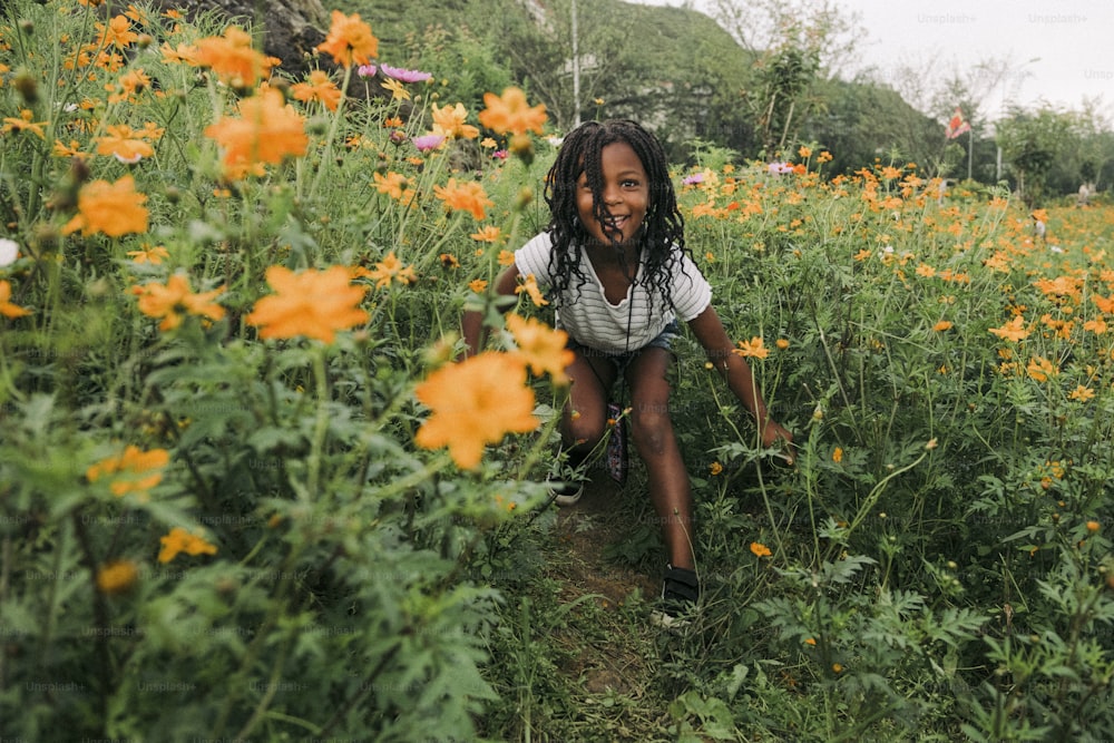 Ein kleines Mädchen, das in einem Blumenfeld kniet