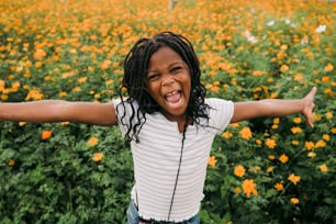 a young girl with dreadlocks standing in a field of flowers