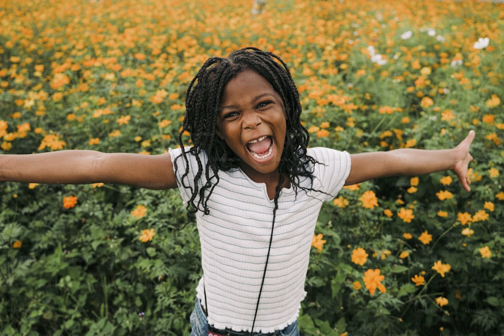 a young girl with dreadlocks standing in a field of flowers