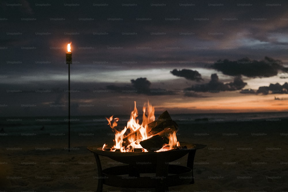 a fire pit sitting on top of a sandy beach