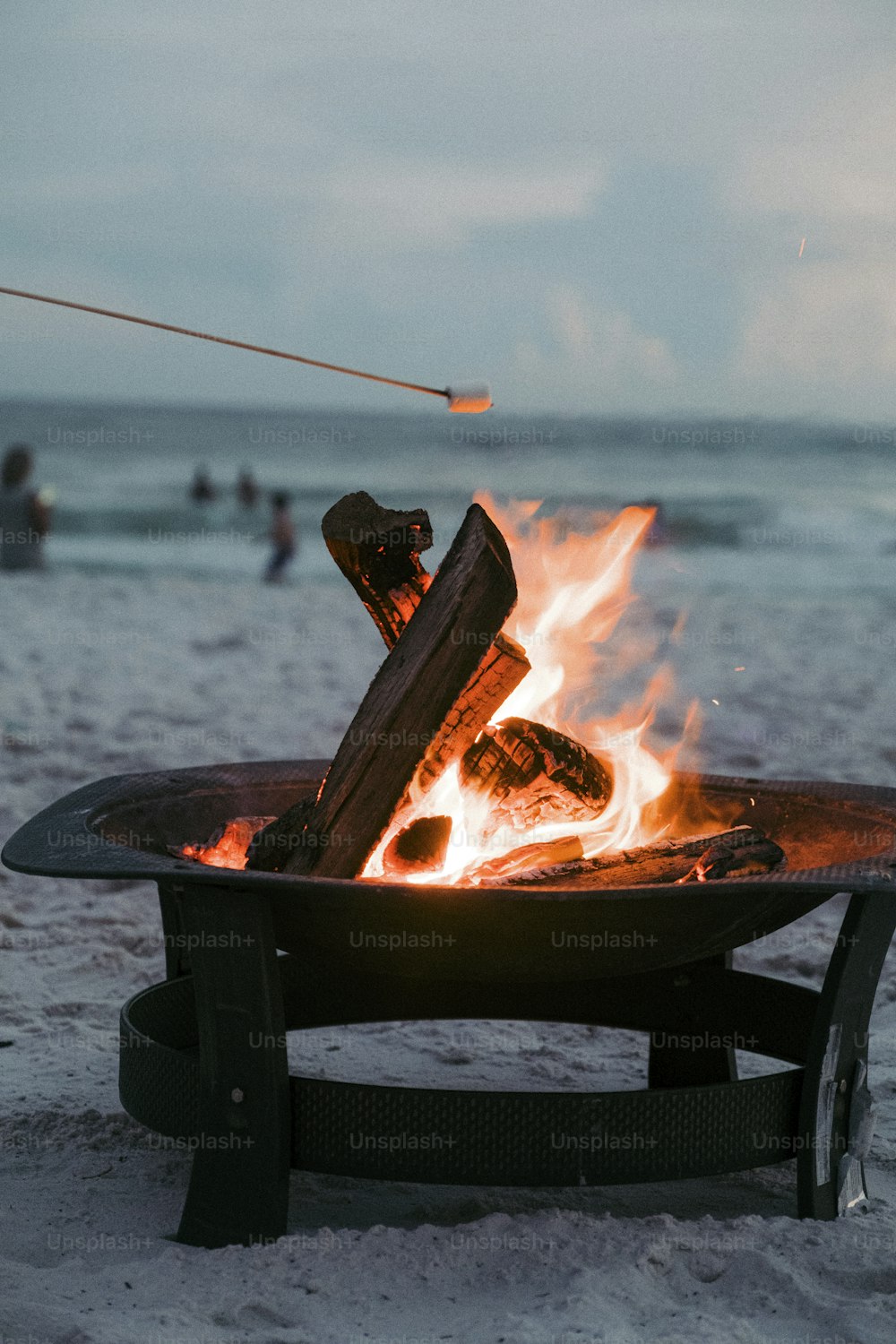 a fire pit sitting on top of a sandy beach