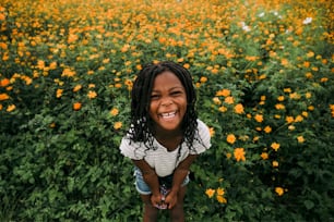 Une petite fille debout dans un champ de fleurs
