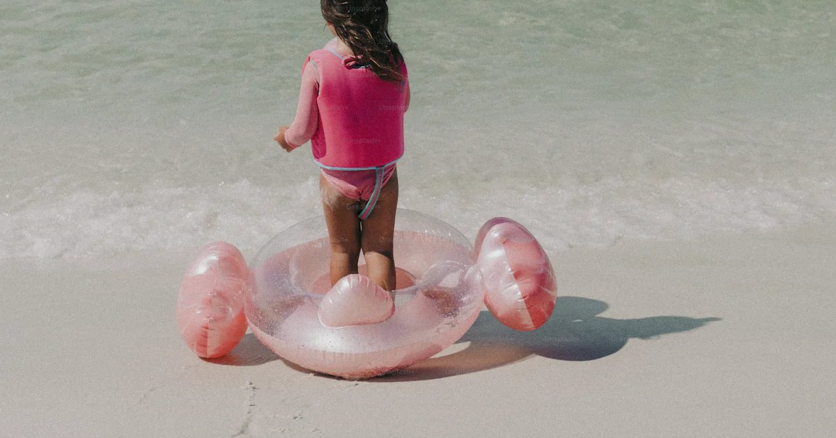 Little Girl Inflatable Raft A little girl in a pink shirt standing on an inflatable float at the ...