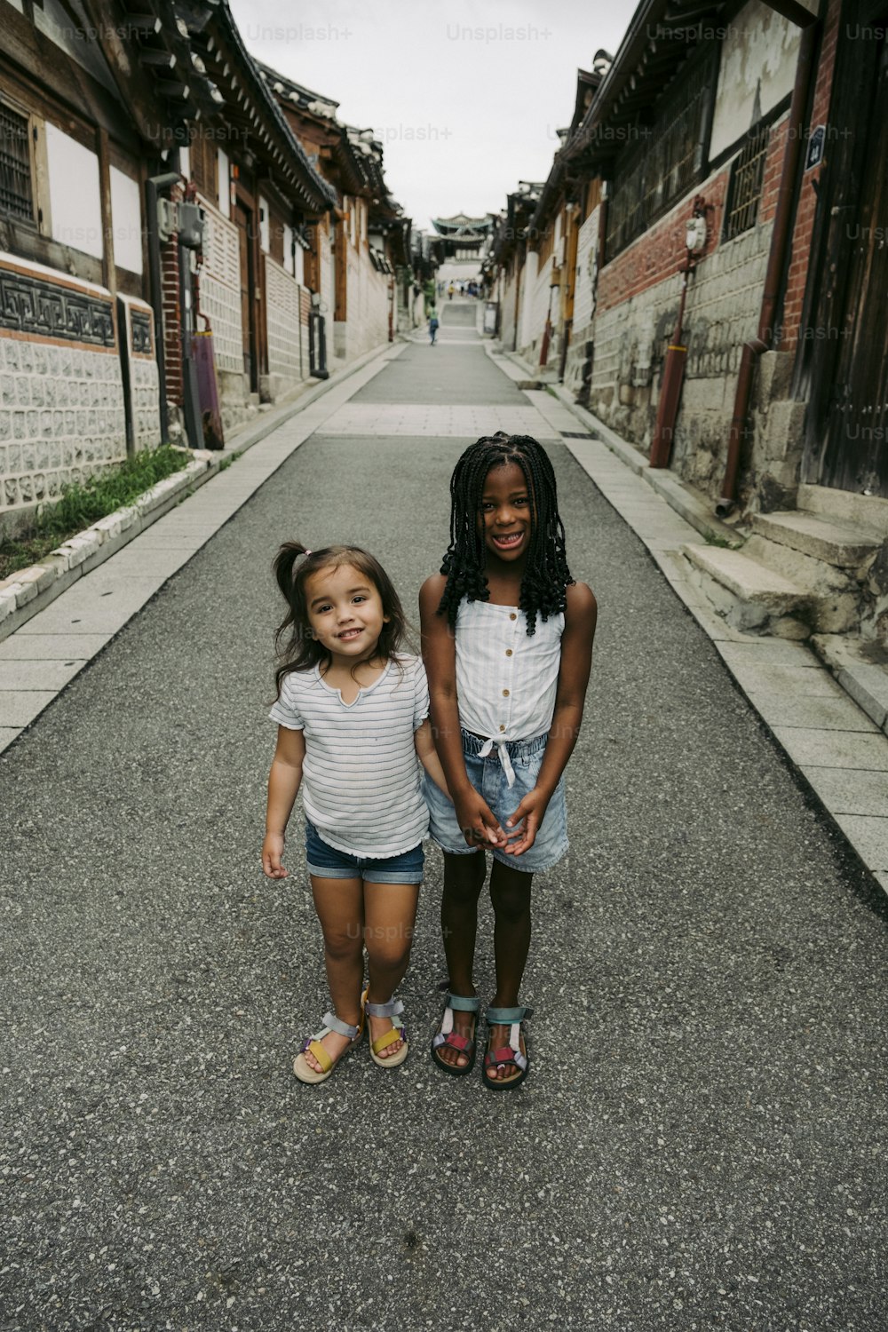 two little girls standing in the middle of a street