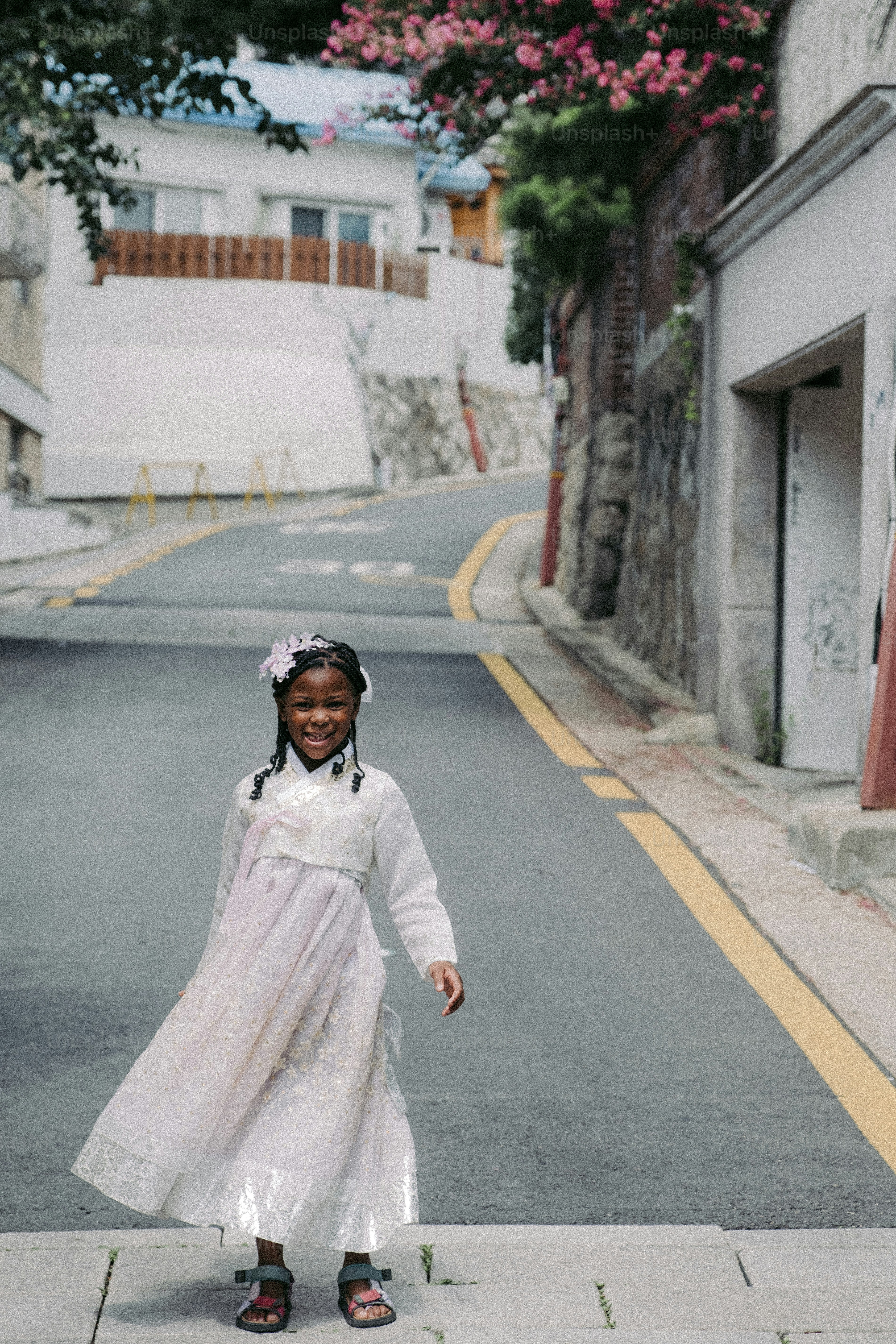 Una niña con un vestido blanco parada en una calle