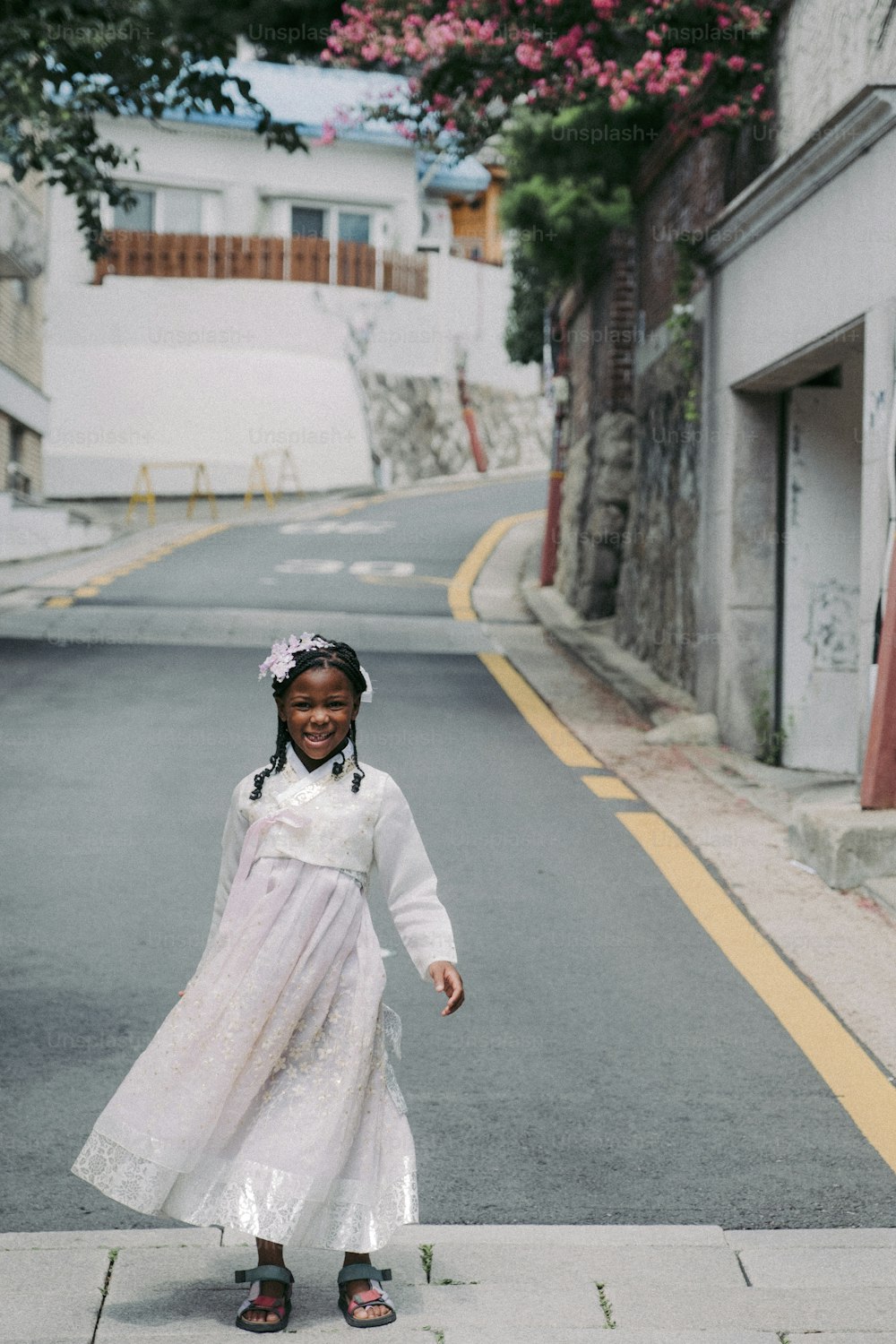 a little girl in a white dress standing on a street