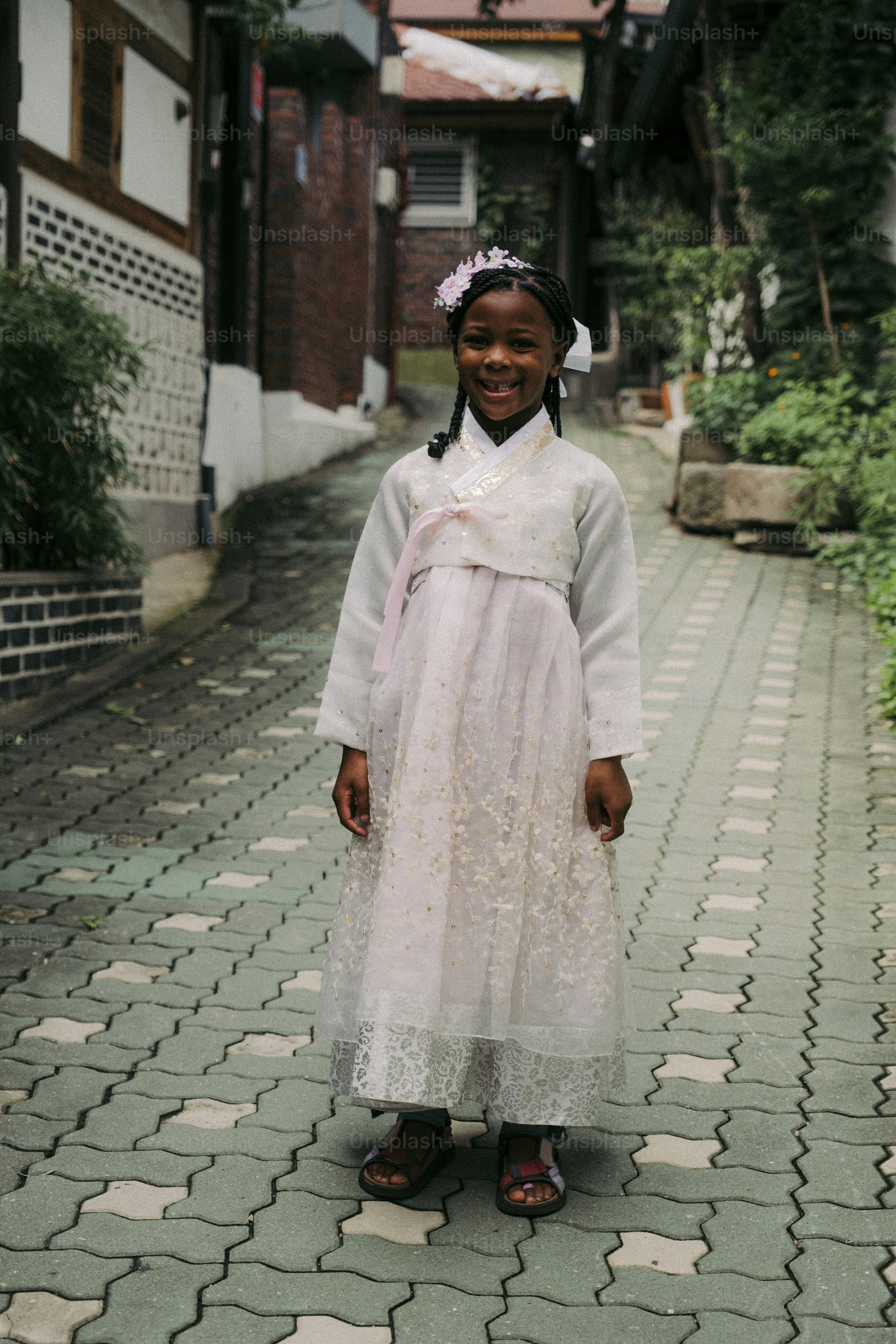uma jovem em um vestido branco em pé em uma rua de paralelepípedos