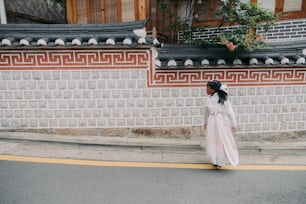 Eine Frau in einem weißen Kleid geht die Straße entlang
