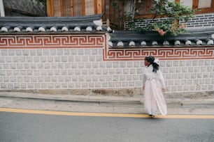 a woman in a white dress is walking down the street