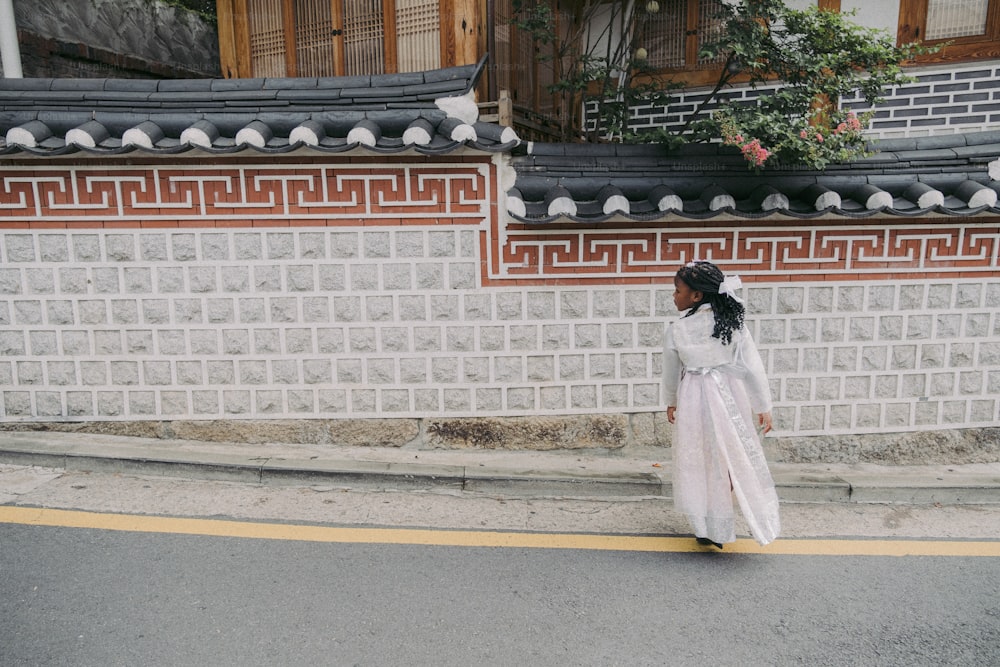 Una donna in un vestito bianco sta camminando per strada