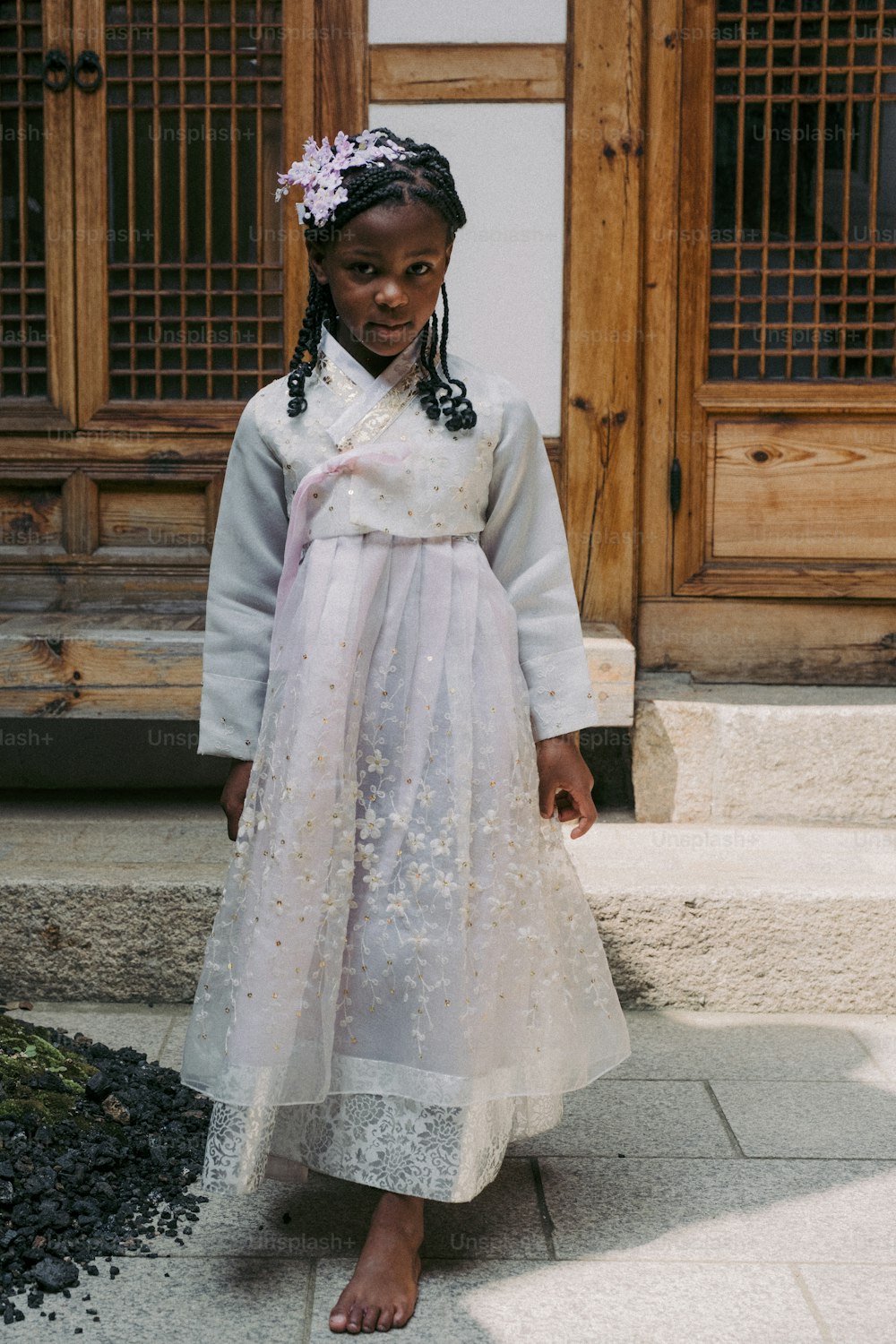 a little girl in a dress standing on a sidewalk