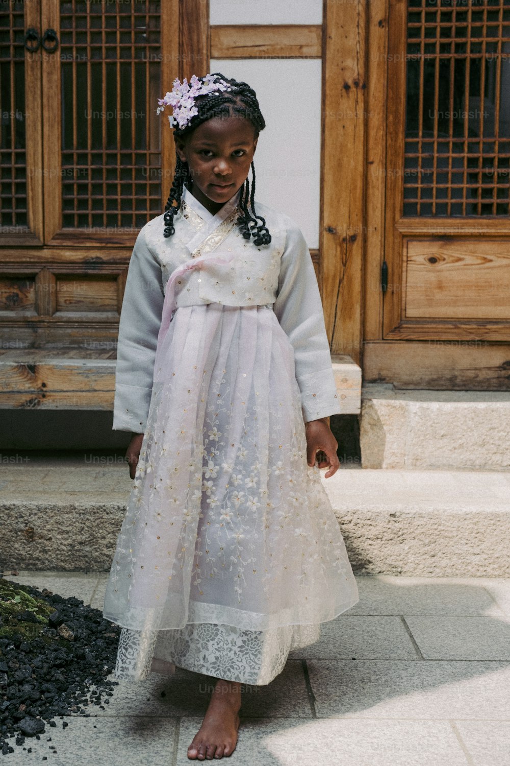 a little girl in a dress standing on a sidewalk