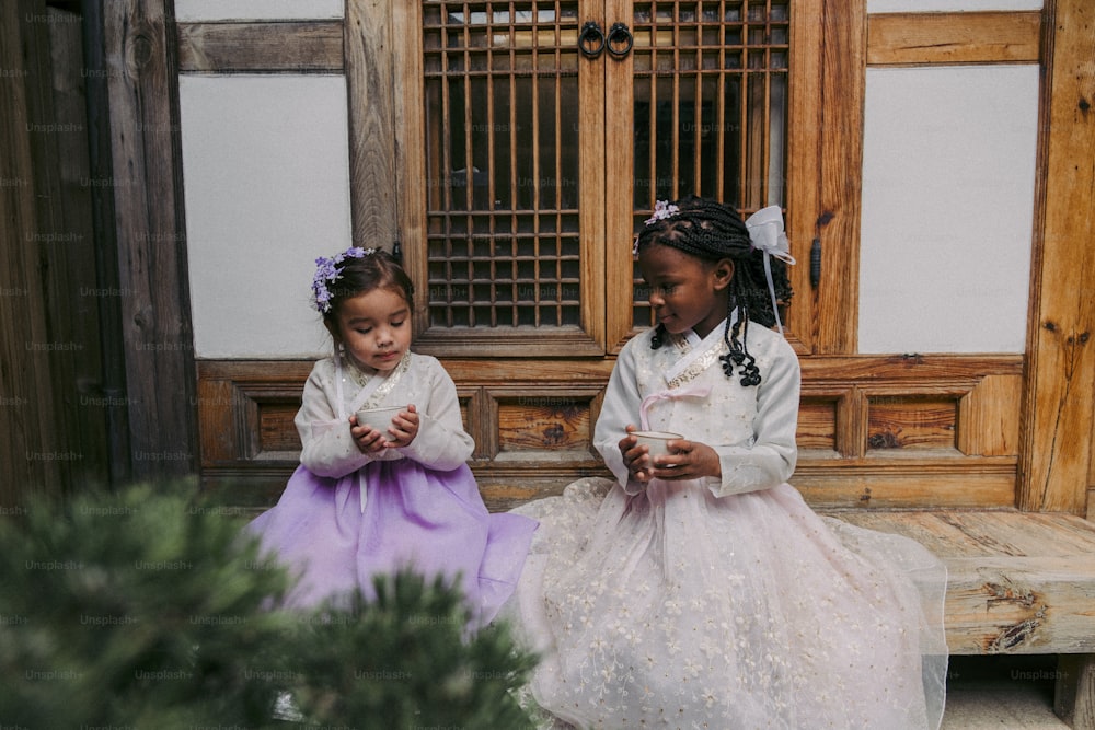 Dos chicas jóvenes sentadas en un banco mirando sus teléfonos celulares