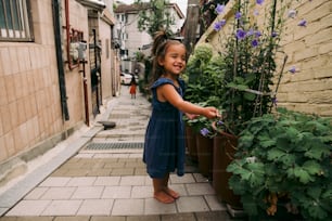 a little girl that is standing next to a plant