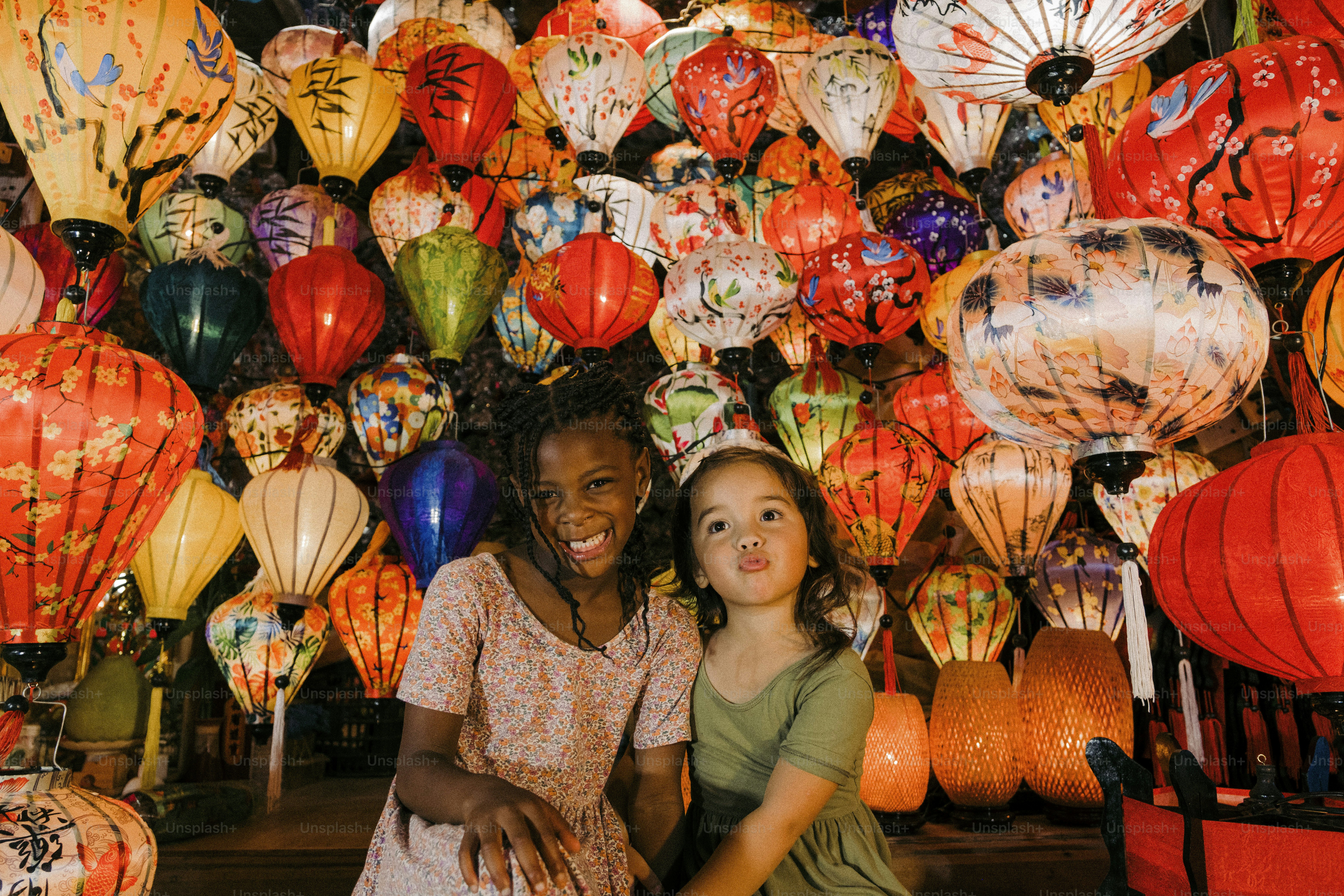 A narrow cobblestone street glowing with hundreds of floating paper lanterns, children laughing as elders whisper old tales under the soft evening sky.