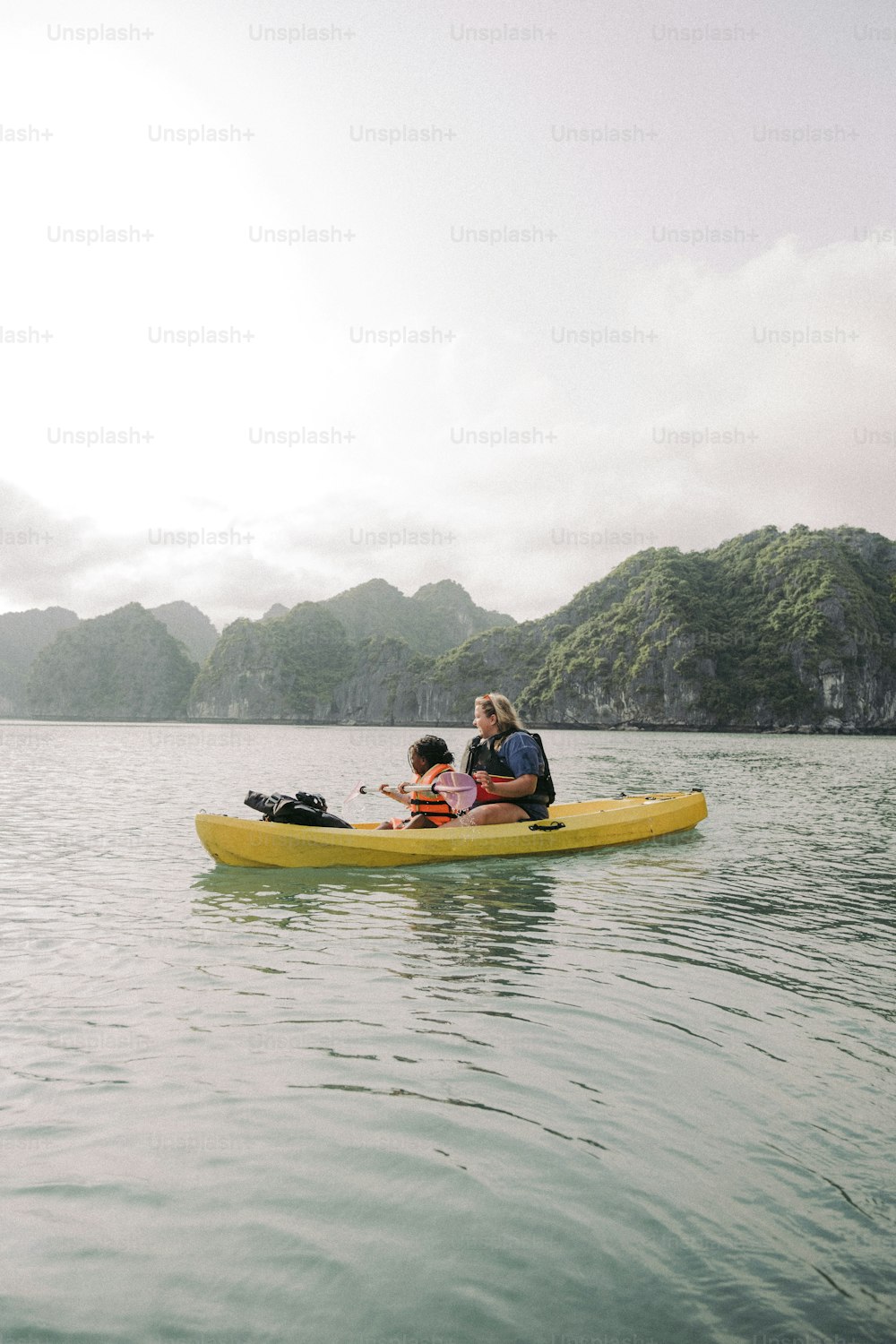 a woman and two children in a yellow kayak