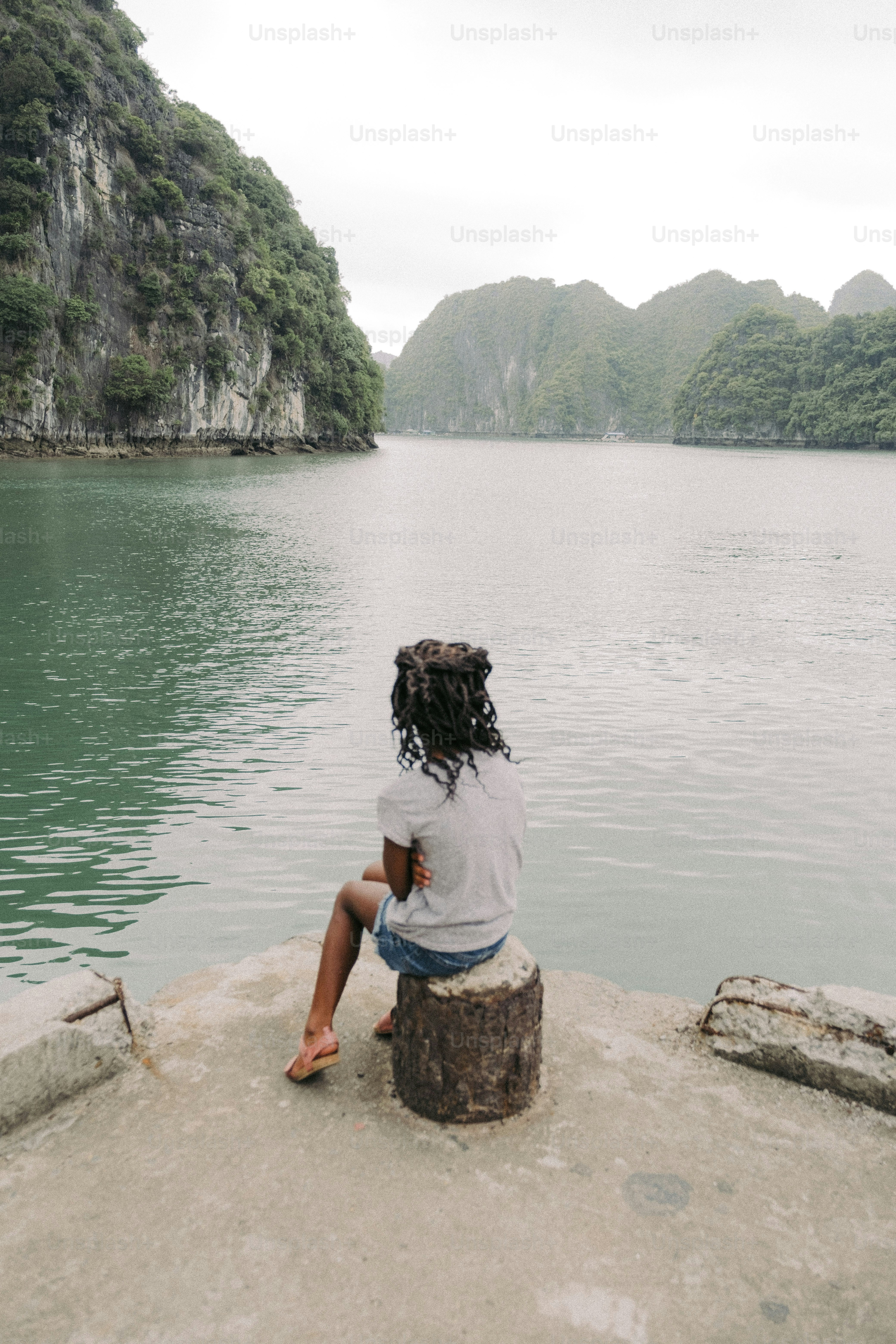a person sitting on a rock near a body of water