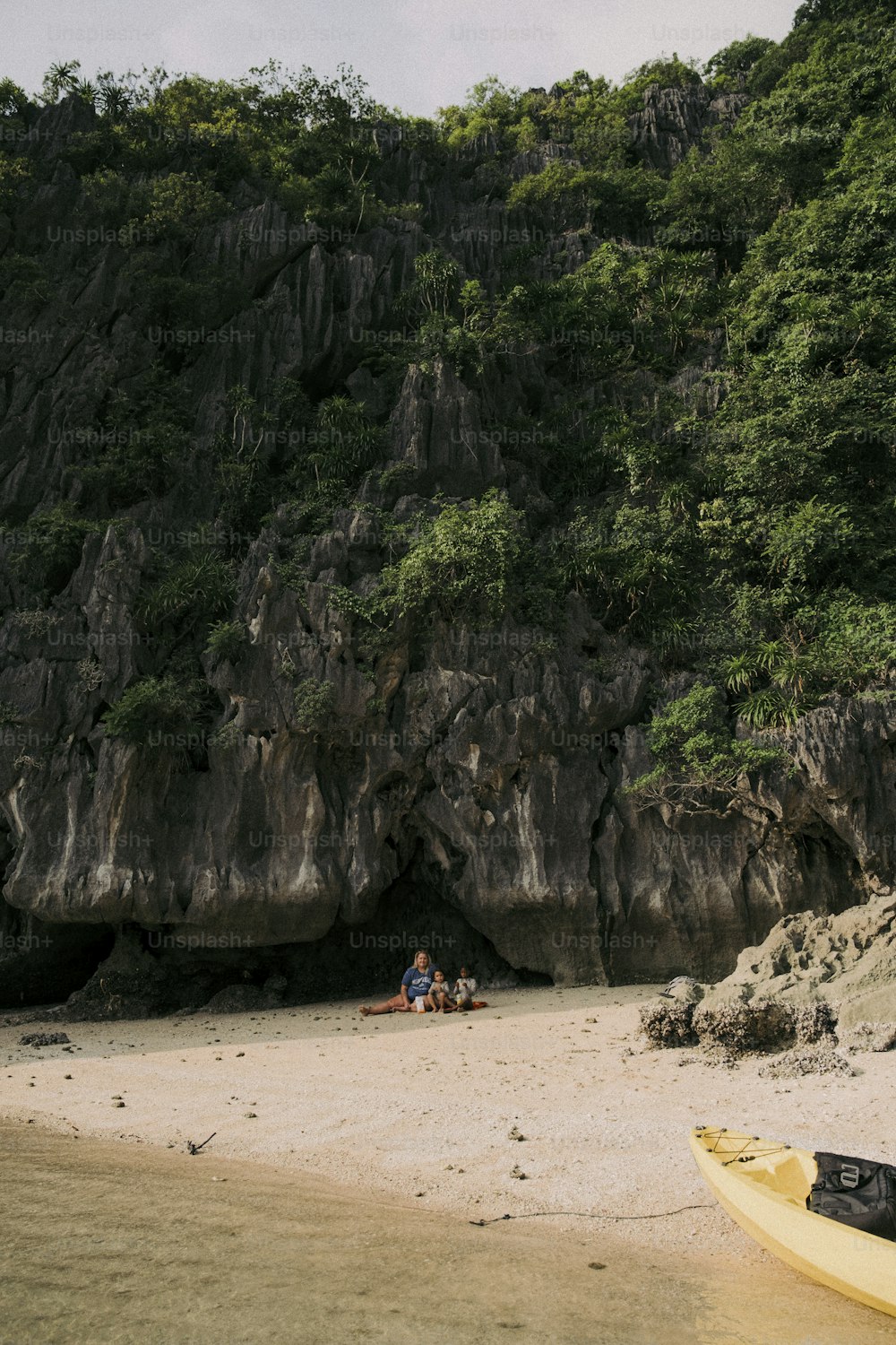 a couple of people sitting on top of a sandy beach