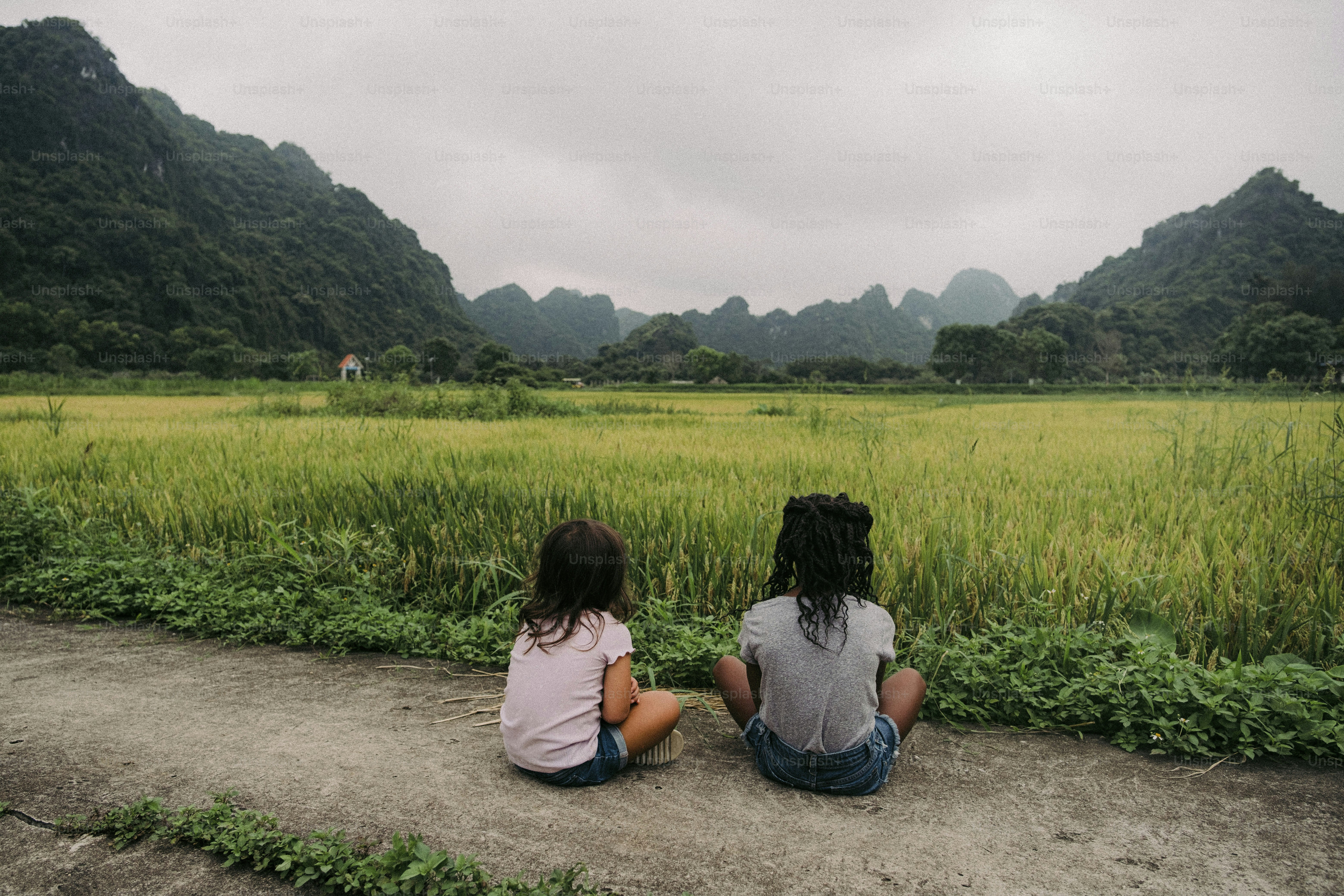 a couple of people sitting on top of a dirt road