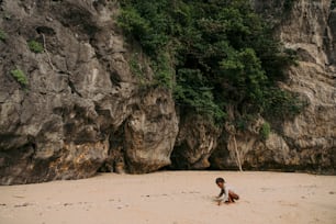 Eine Person, die an einem Strand neben einer Klippe kniet