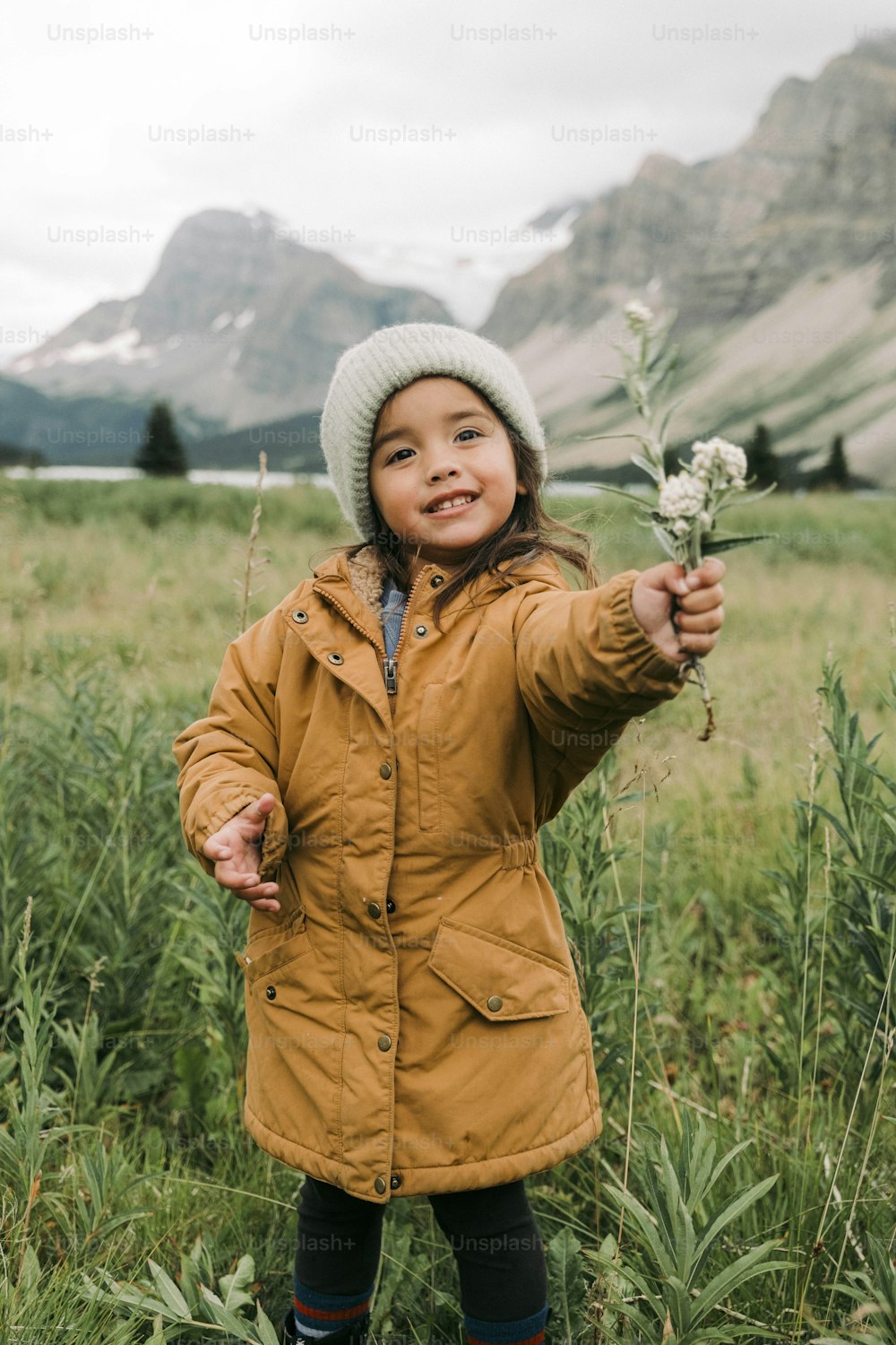 a little girl standing in a field holding a flower