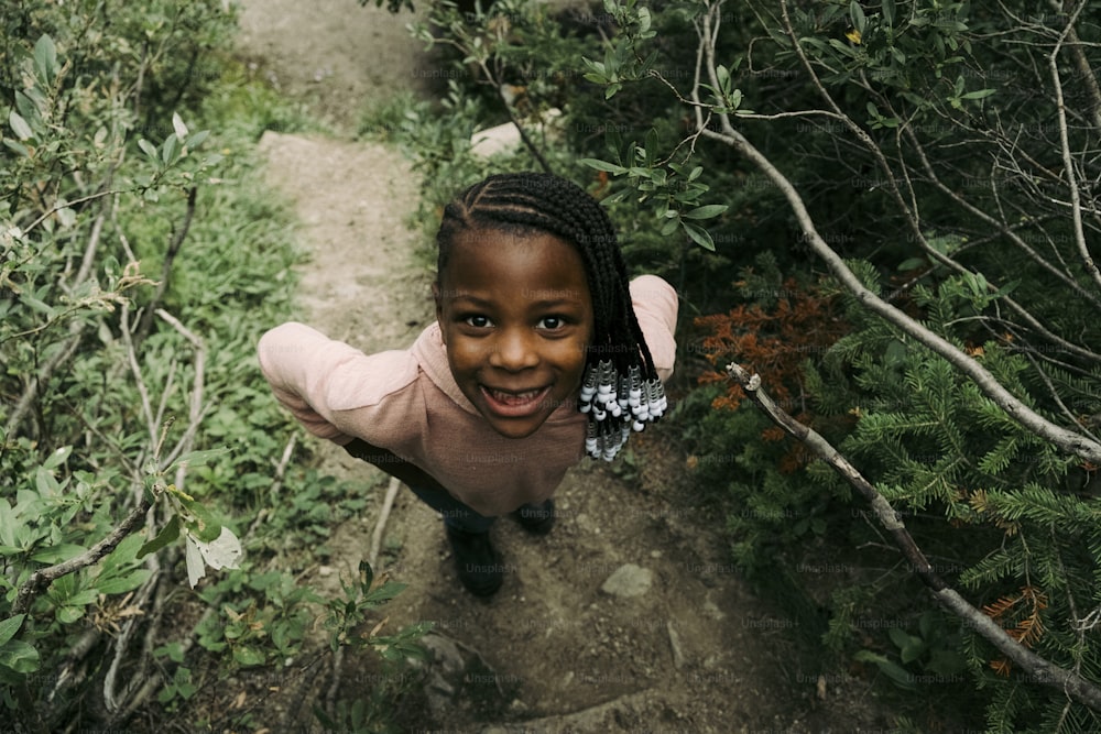 a little girl standing in the middle of a forest