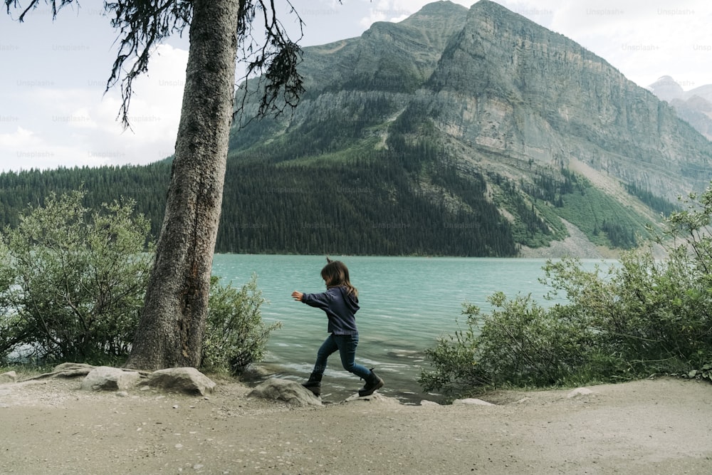 a woman is running near a lake with a mountain in the background