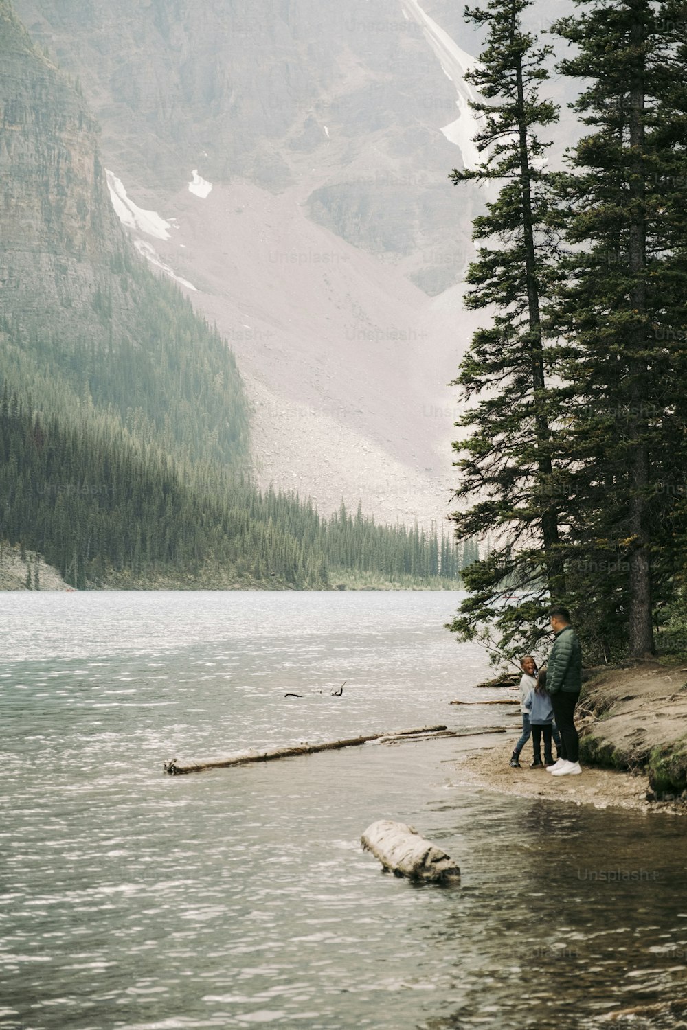 a man and a woman standing on the shore of a lake