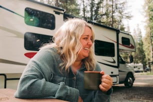 a woman sitting at a table in front of a camper