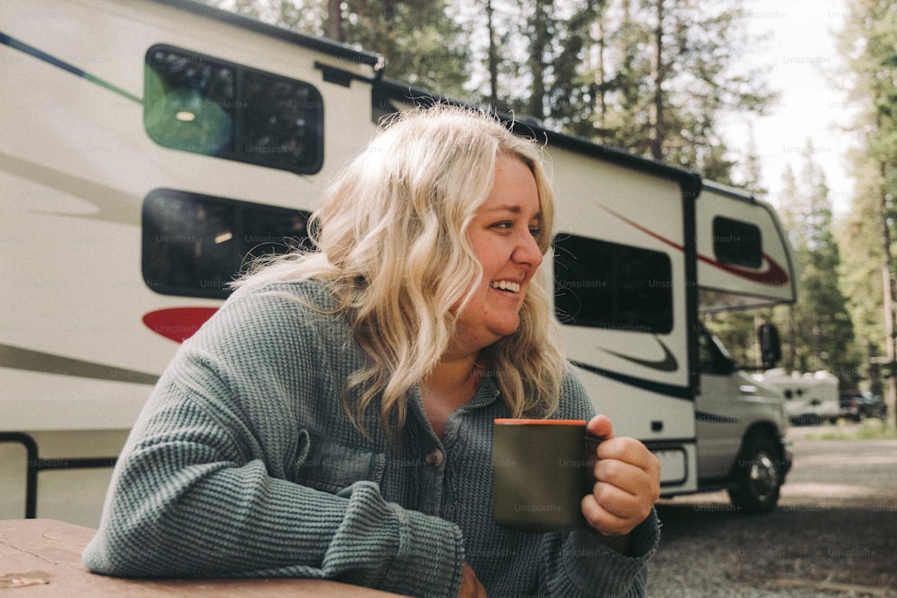 a woman sitting at a table in front of a camper