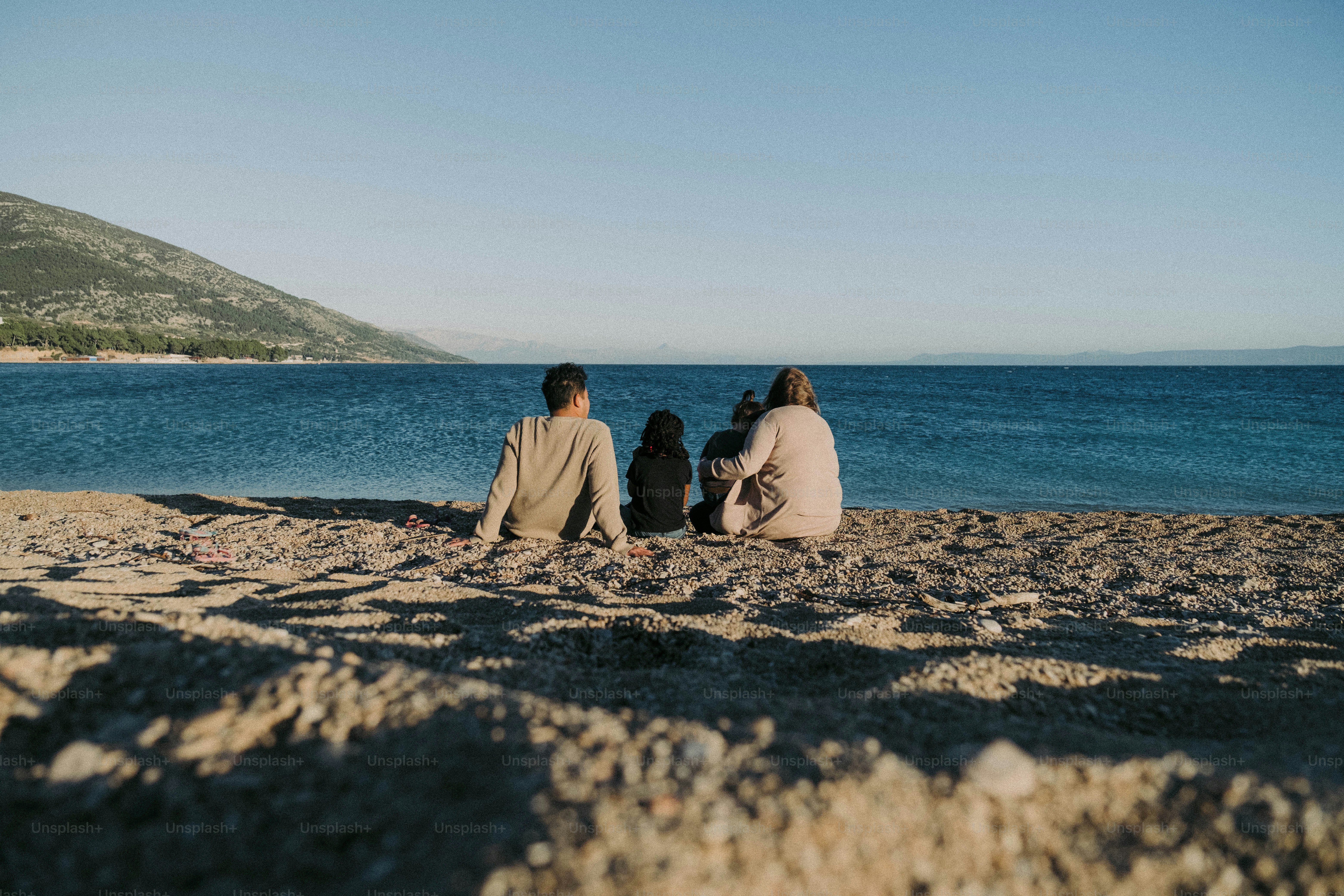 a couple of people sitting on top of a sandy beach