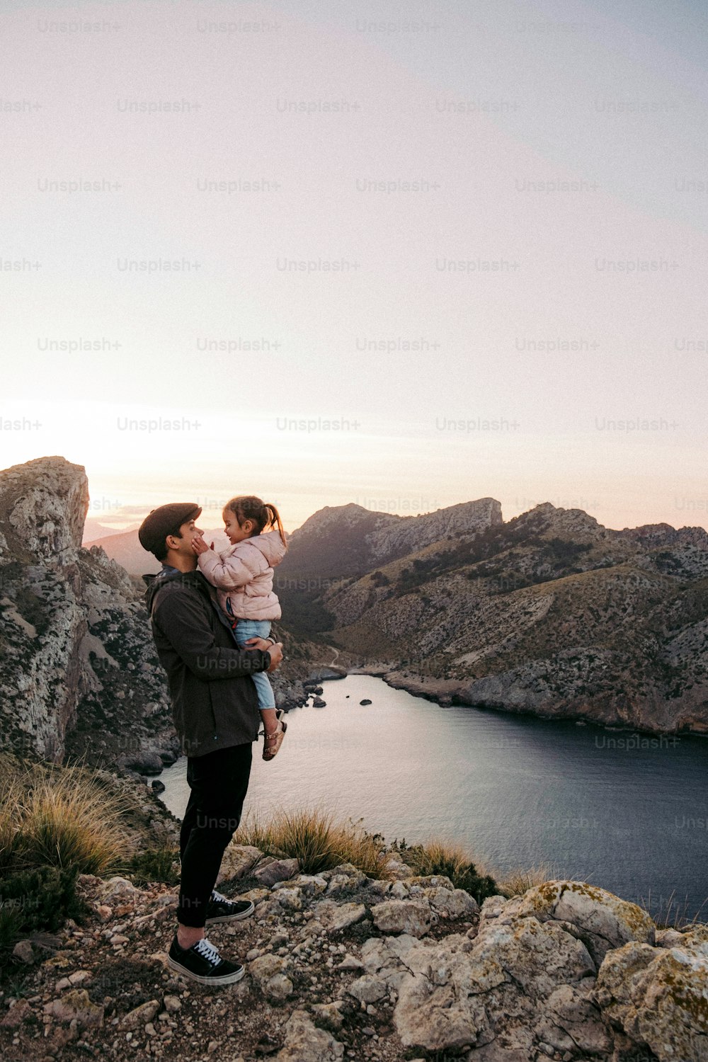 um homem segurando uma criança no topo de uma montanha
