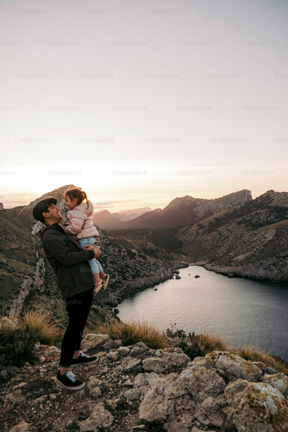 a man holding a little girl on top of a mountain