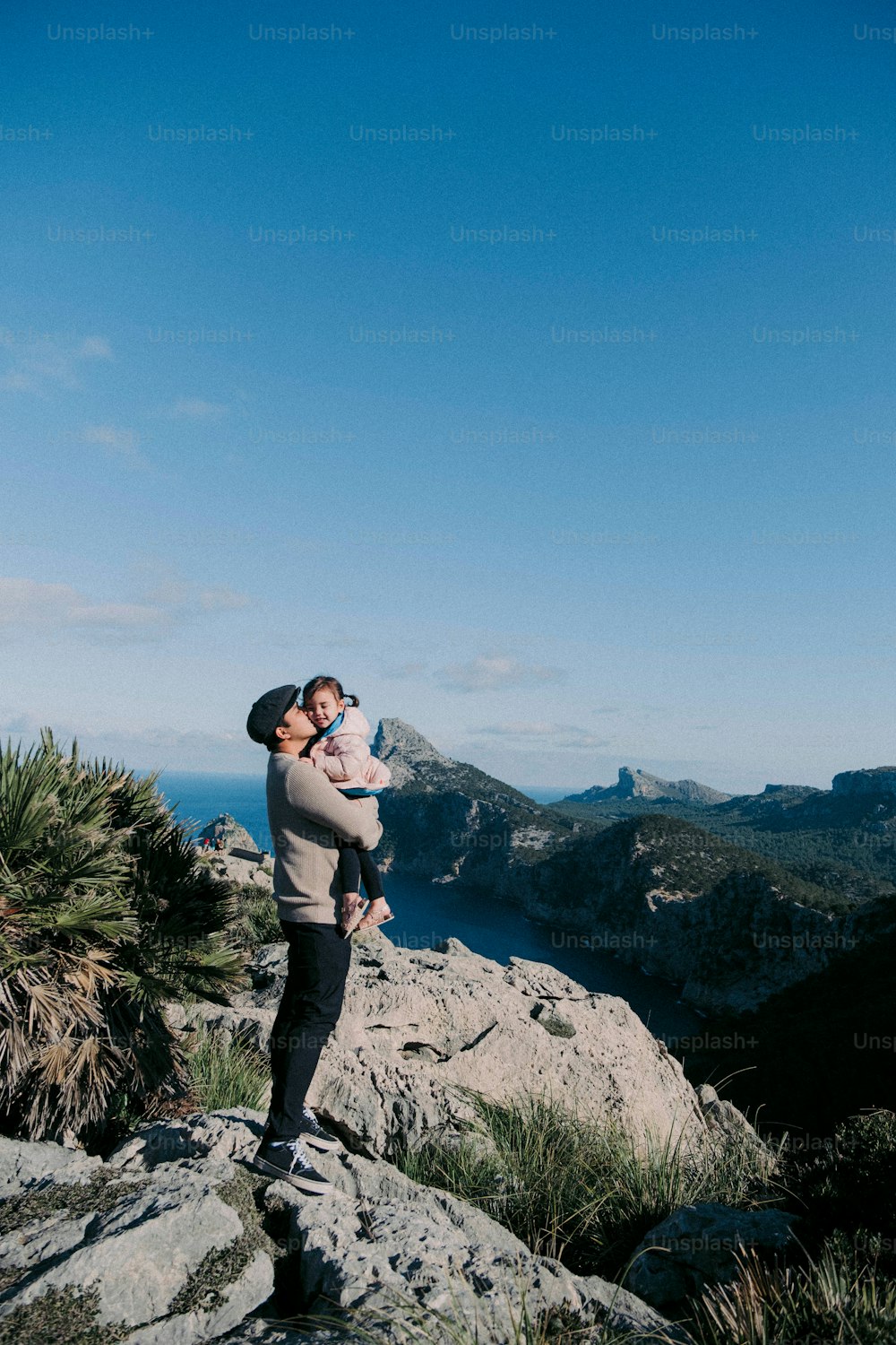 um homem segurando um bebê no topo de uma montanha