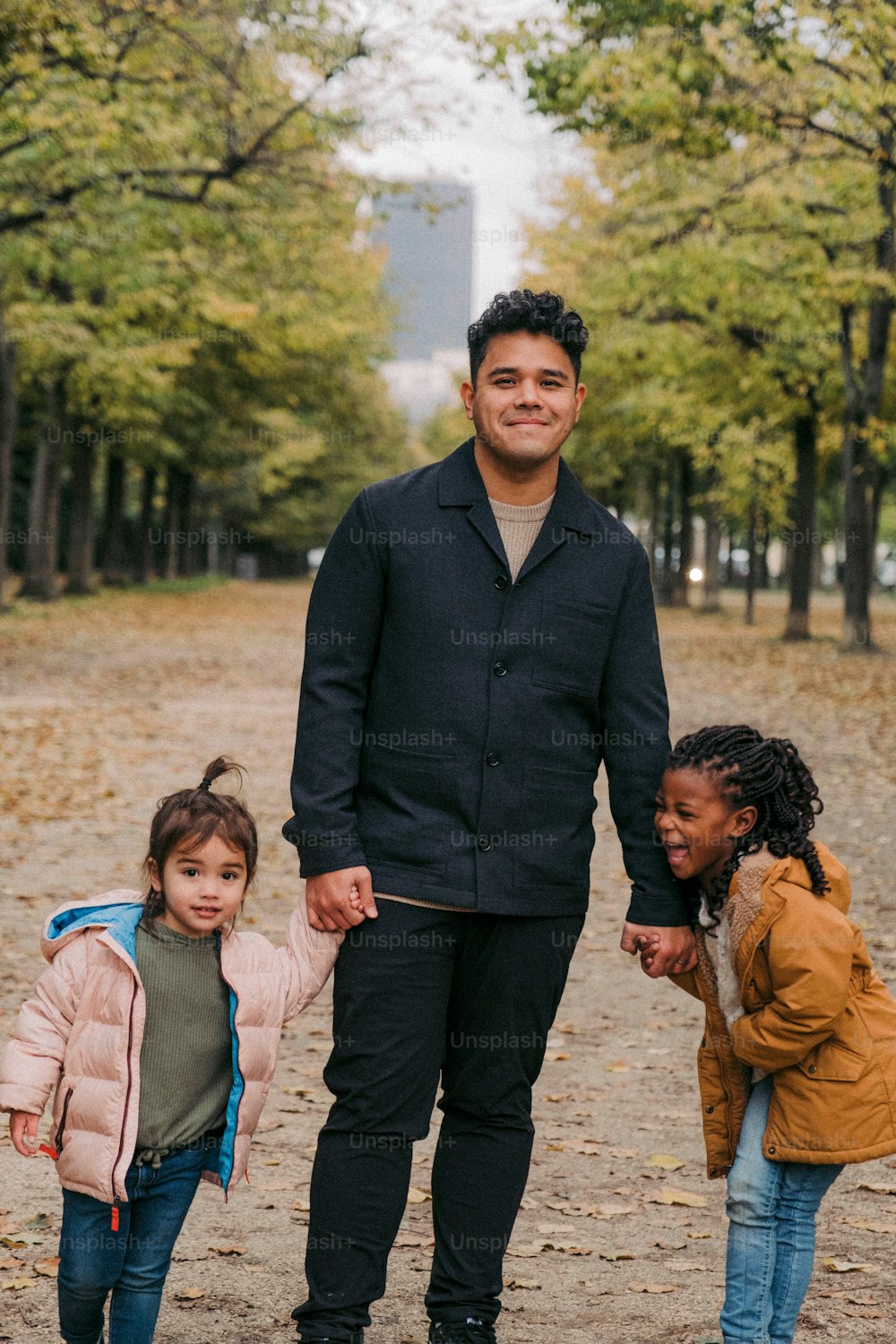 um homem e duas meninas caminhando em um parque