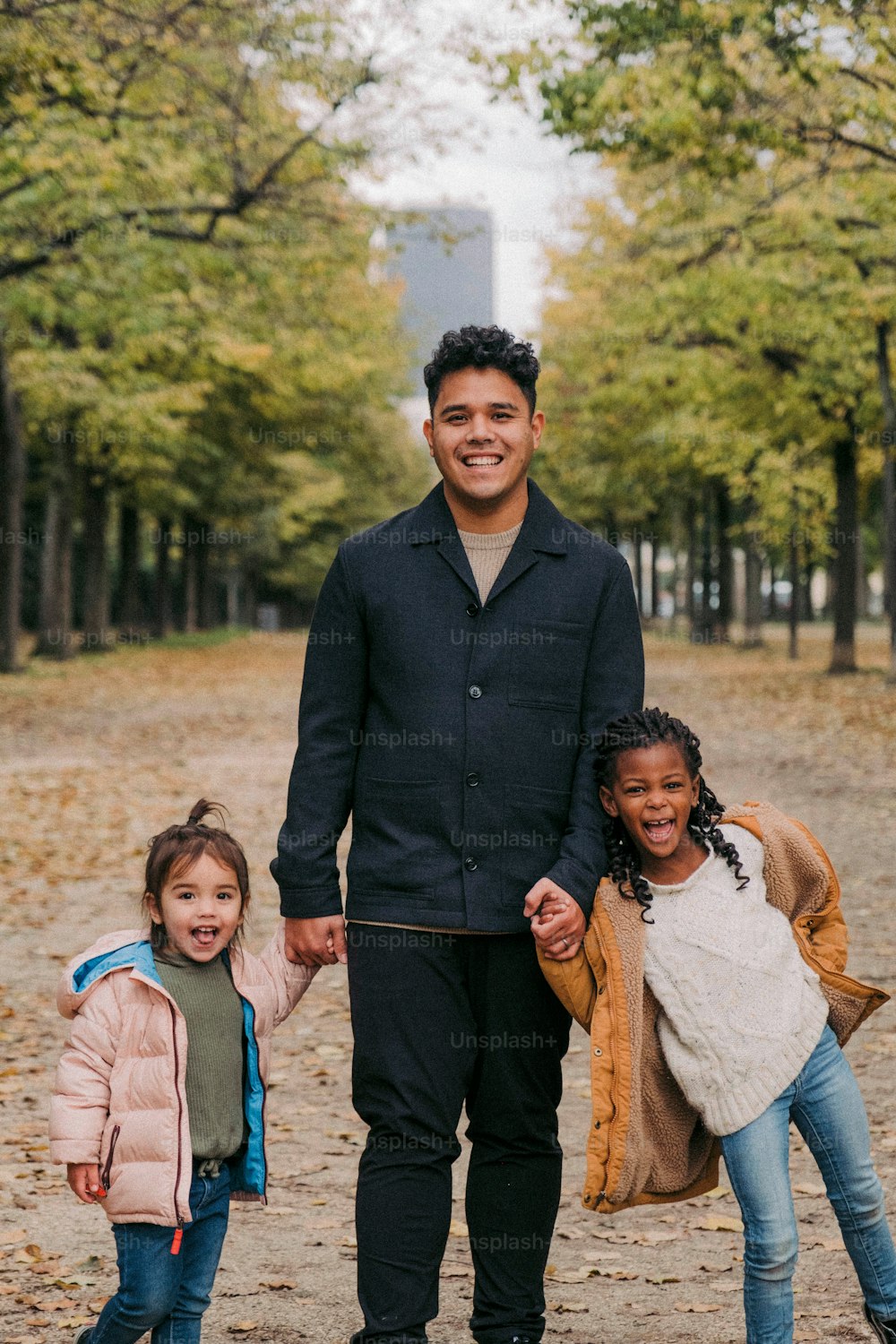 a man and two little girls walking in a park