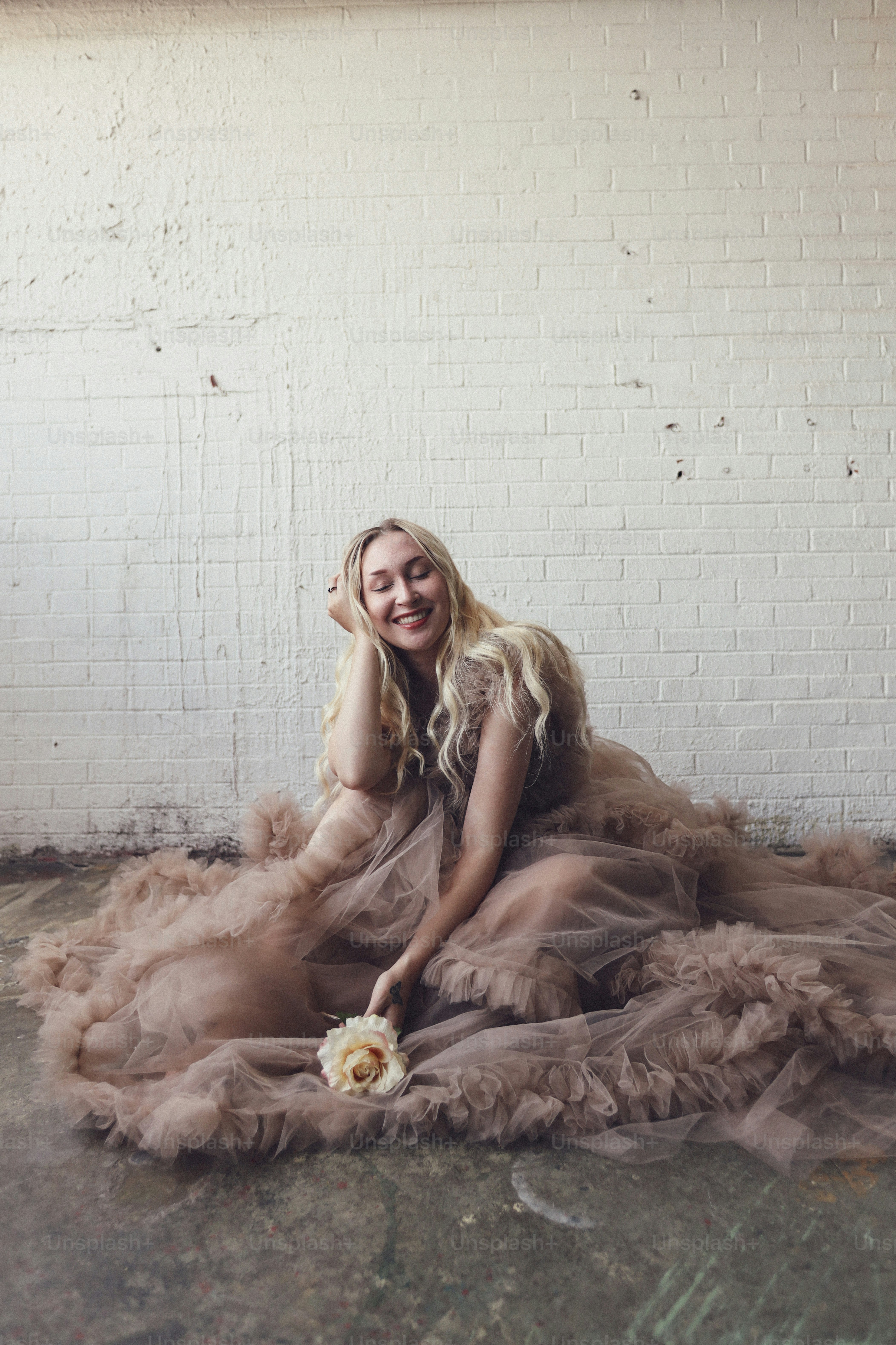 a woman sitting on the ground with a flower in her hand