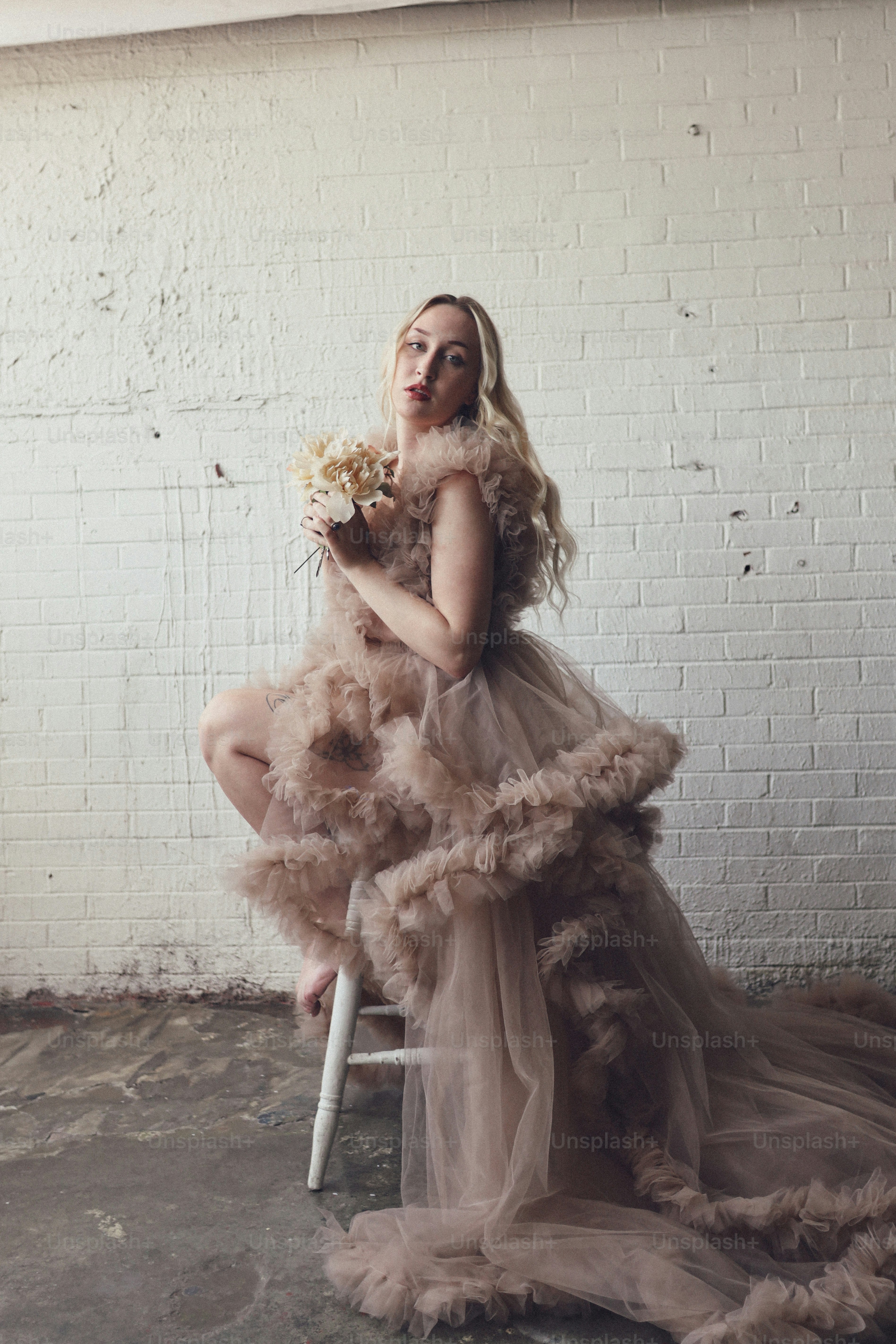 a woman sitting on a stool holding a bouquet of flowers