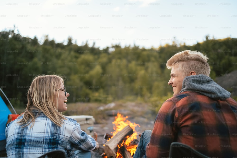 Un homme et une femme assis près d’un feu de camp