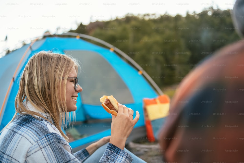 テントの前でホットドッグを食べる女性