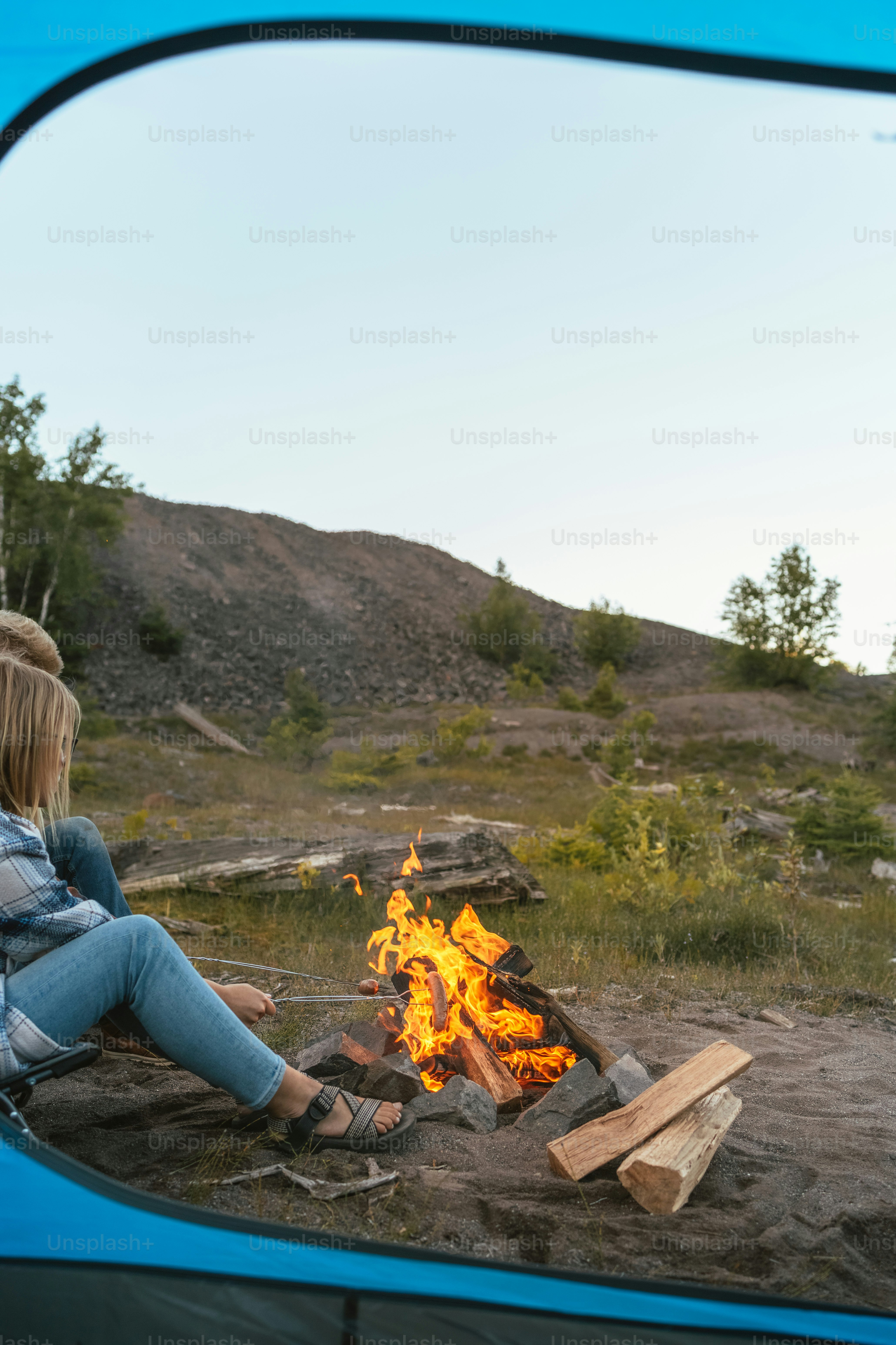 Eine Frau sitzt vor einem Lagerfeuer