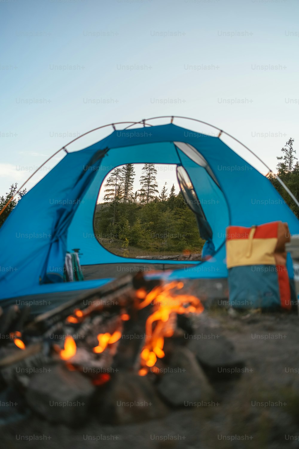 a blue tent sitting next to a fire