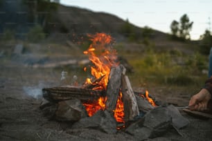 une personne assise devant un feu de camp
